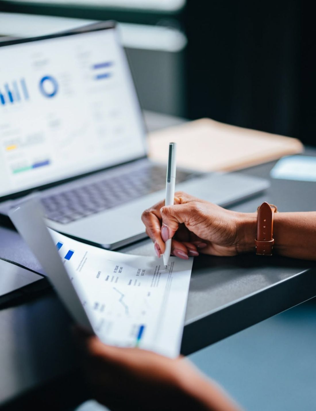 Analista revisando gráficas de rendimiento financiero en laptop y en papel